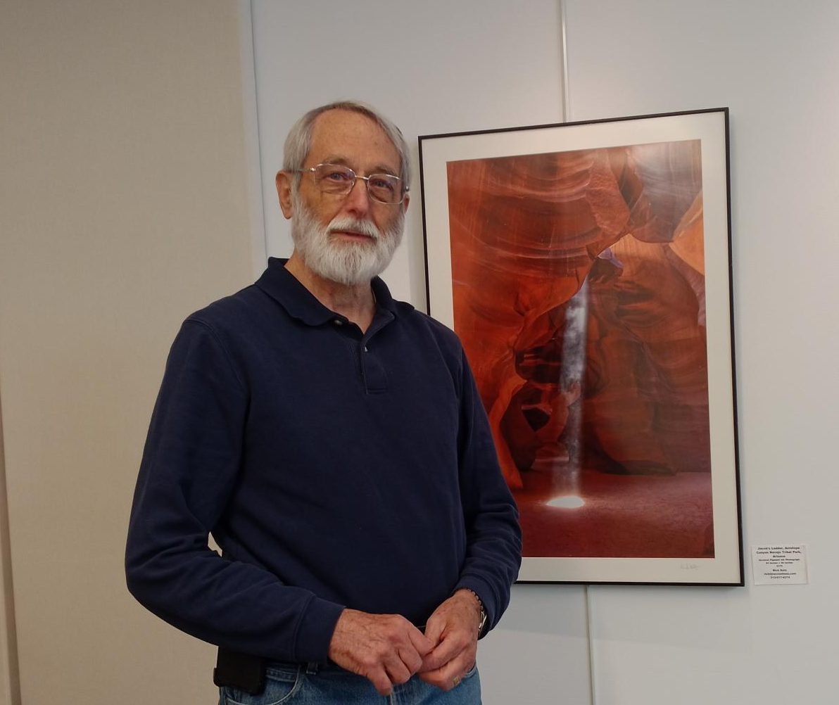 Photographer Rick Katz standing in front of one of his photographs.